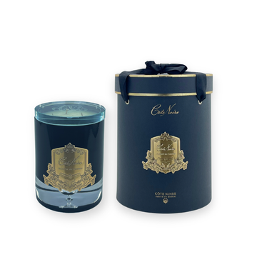 Blue candle with decorative label and matching cylindrical box on a white background